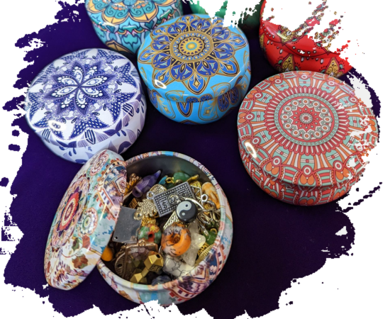 Decorative tin with lid open and many different charms inside and multiple closed tins of different designs and colors 