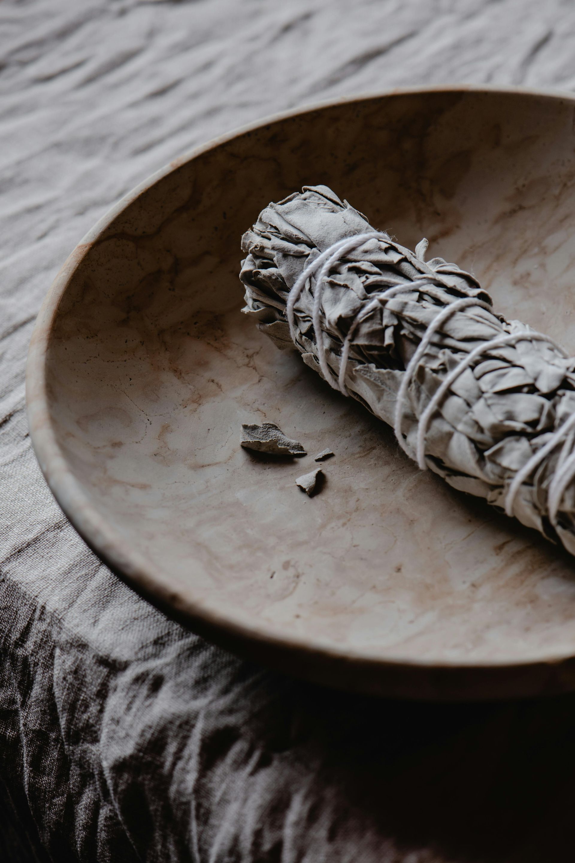A white sage stick is sitting on a wooden plate.