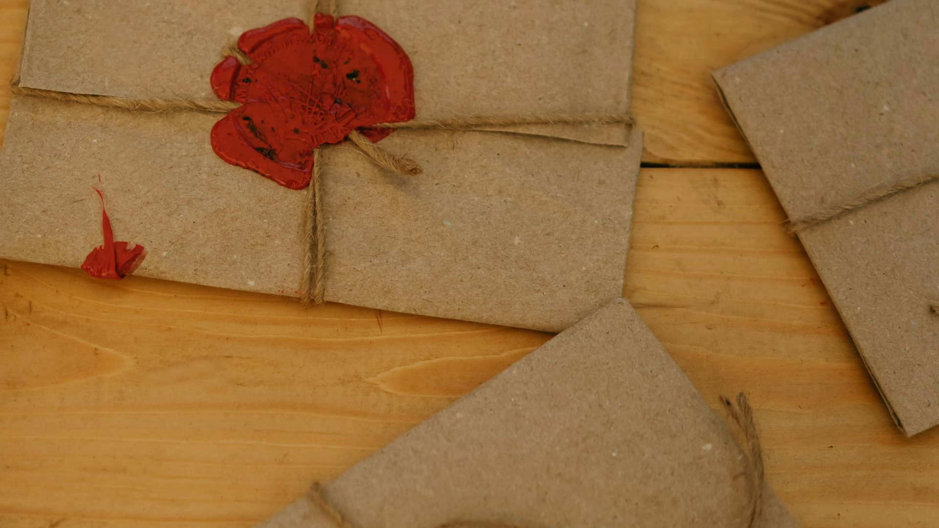 Brown paper envelopes tied with twine, sealed with red wax, on a wooden surface.