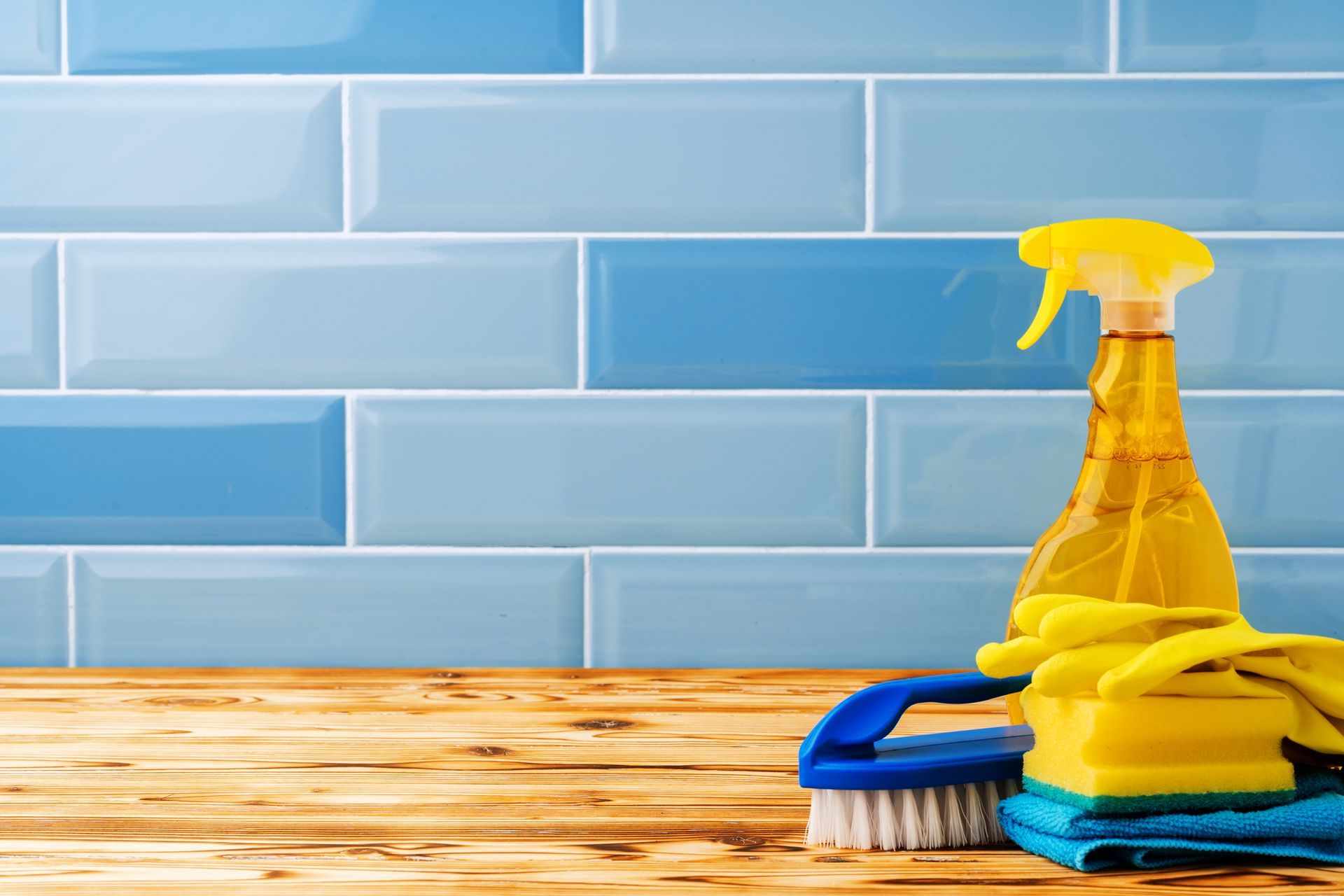 A wooden table topped with cleaning supplies and a spray bottle.