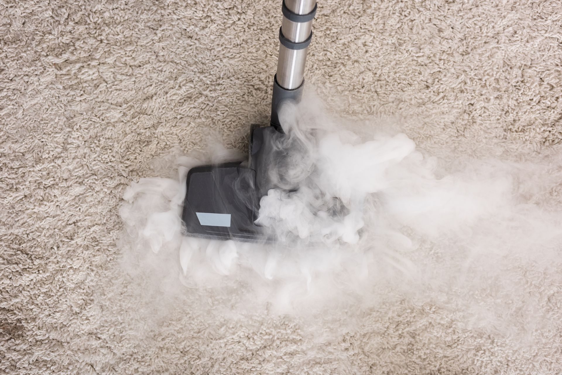 A vacuum cleaner is cleaning a carpet with smoke coming out of it.