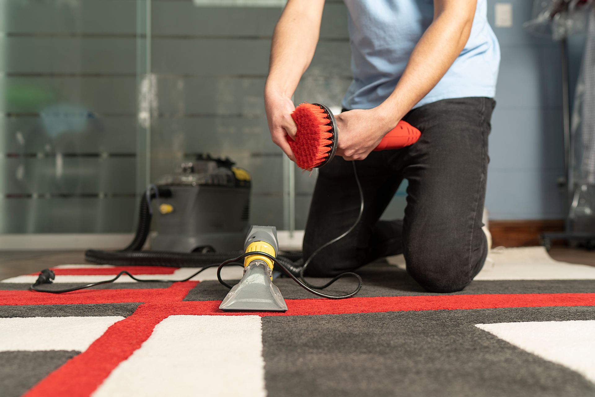 A person is cleaning a rug with a vacuum cleaner.