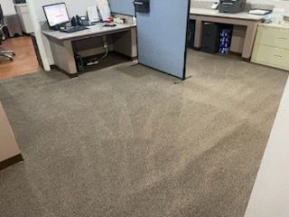 A carpeted floor in an office with a desk and a computer.