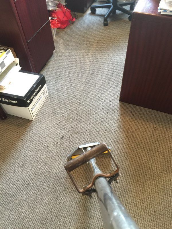 A bicycle pedal is sitting on a carpeted floor in a room.