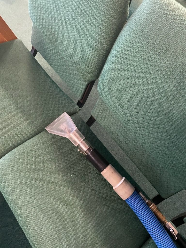 A vacuum cleaner is sitting on top of a green chair.