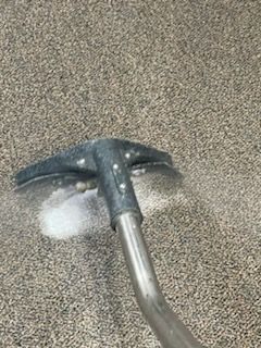 A vacuum cleaner is being used to clean a carpet.