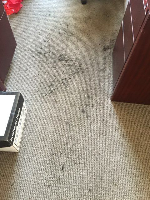 A dirty carpet in a room with a box on the floor.