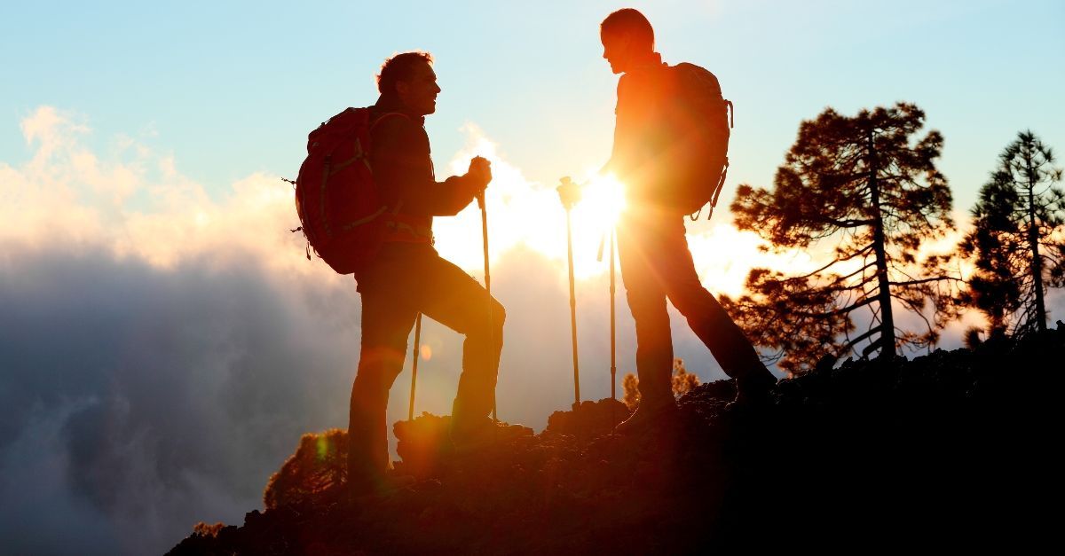 2 men on top of mountain holding hiking poles