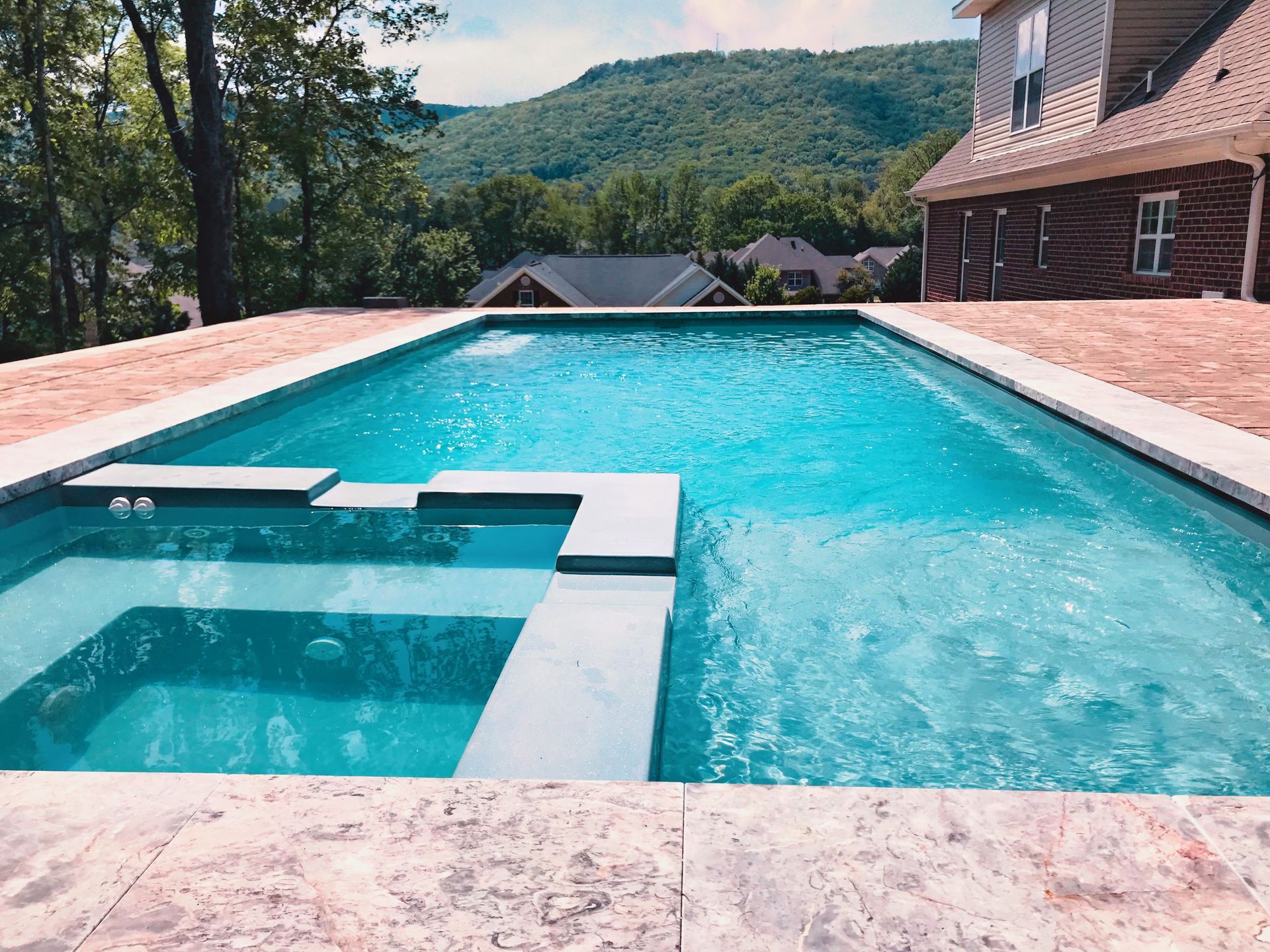 A large swimming pool is surrounded by trees and a house. - Madison, AL - Valley Pools