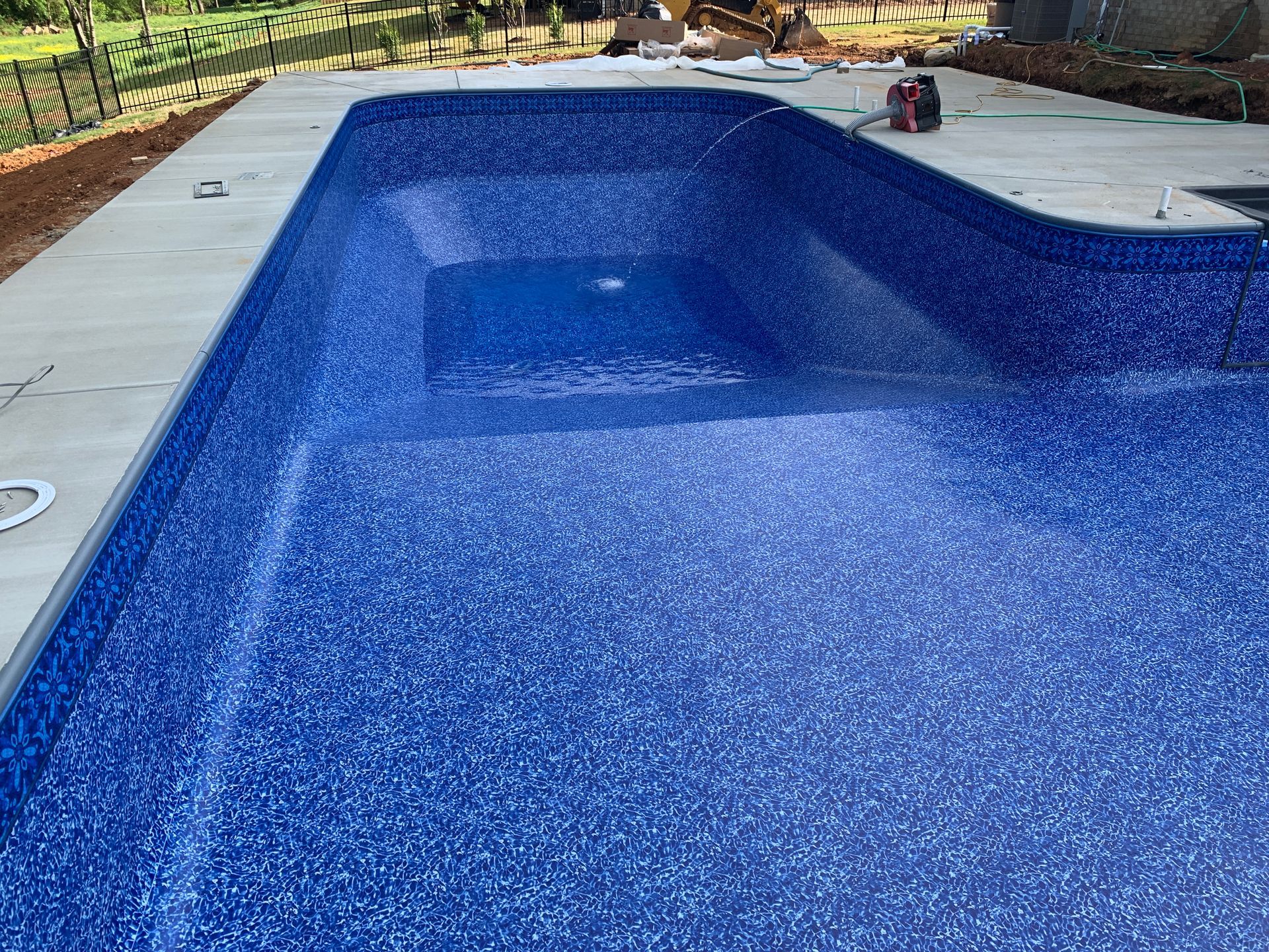 A large blue swimming pool is being built in a backyard. - Madison, AL - Valley Pools
