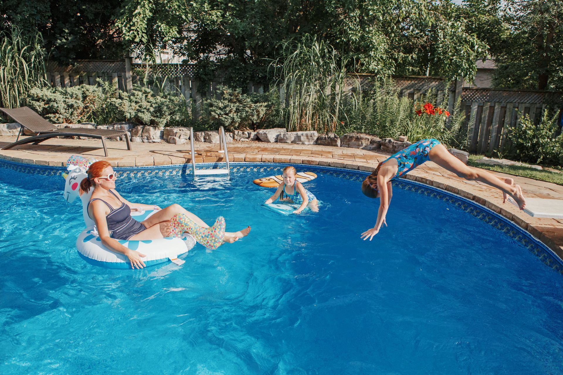 Friends enjoy a backyard pool, floating, diving, and relaxing together.