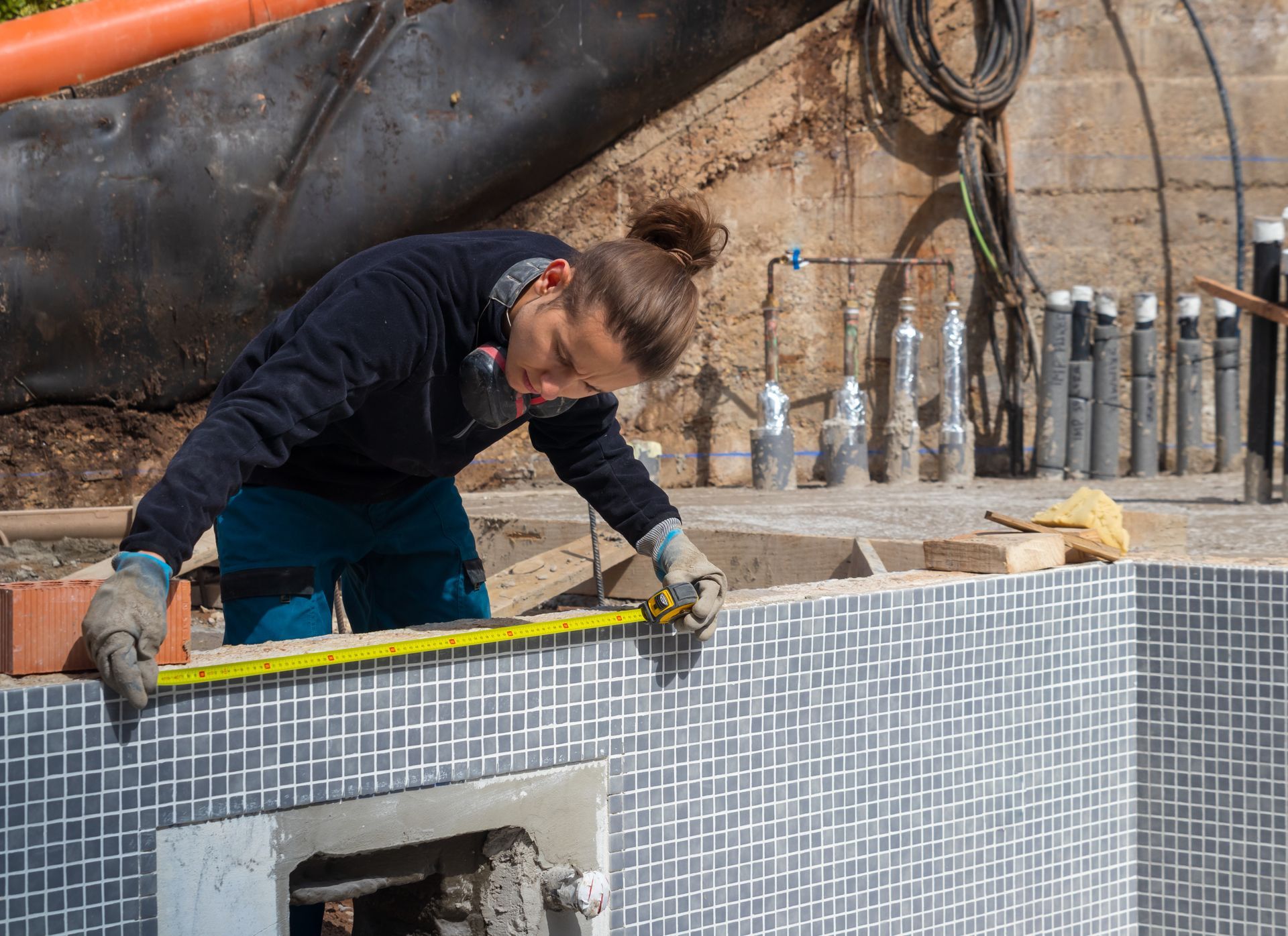 An expert assessing measurements in a pool under construction, representing expert pool contractors.