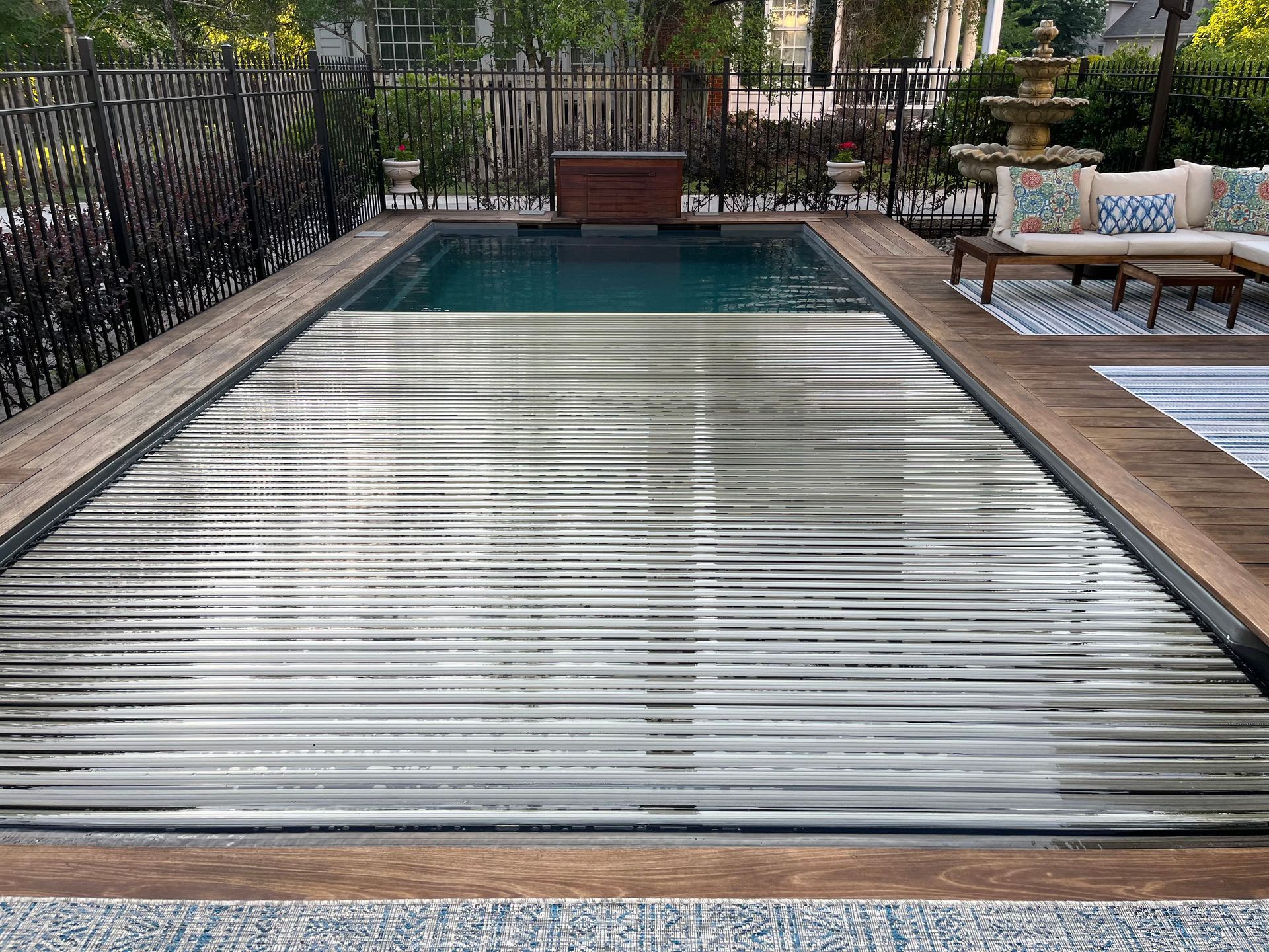 A swimming pool with a stainless steel cover and a wooden deck. - Madison, AL - Valley Pools