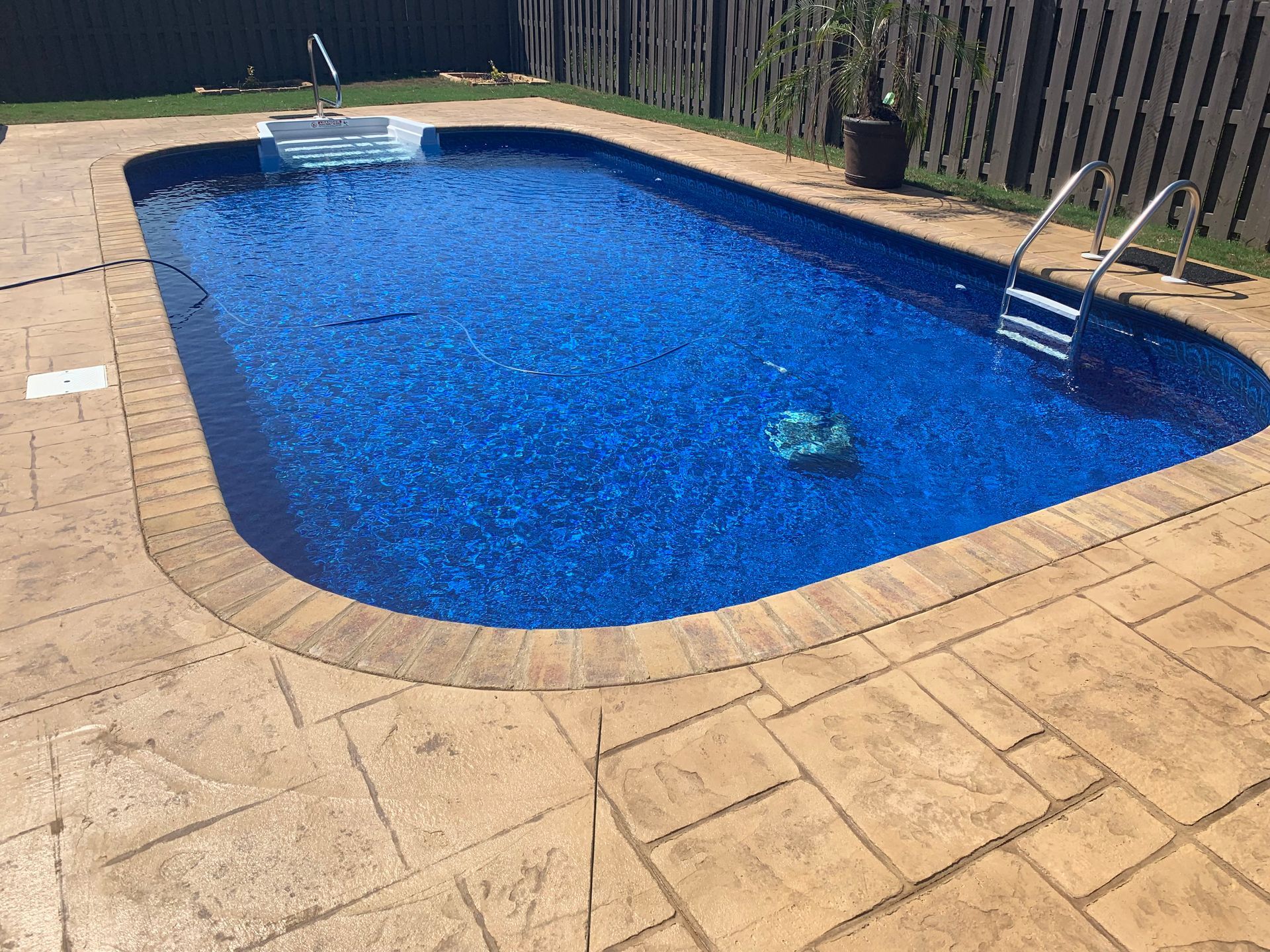 A large swimming pool surrounded by a concrete patio and a fence. - Madison, AL - Valley Pools