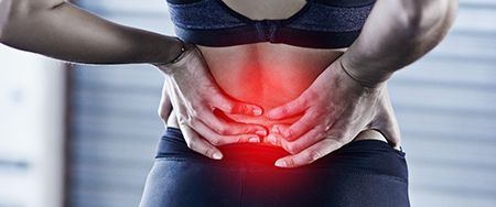 Person holding their lower back with a red highlight indicating pain.