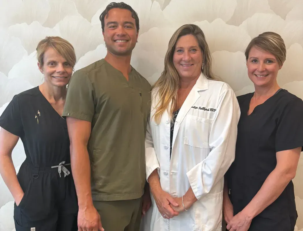 Four healthcare providers posing for a photo in front of a textured wall.