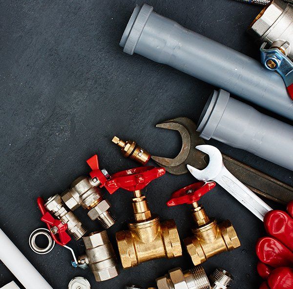 Plumbing Tools On A Grey Surface — Plumber in Central Coast, NSW