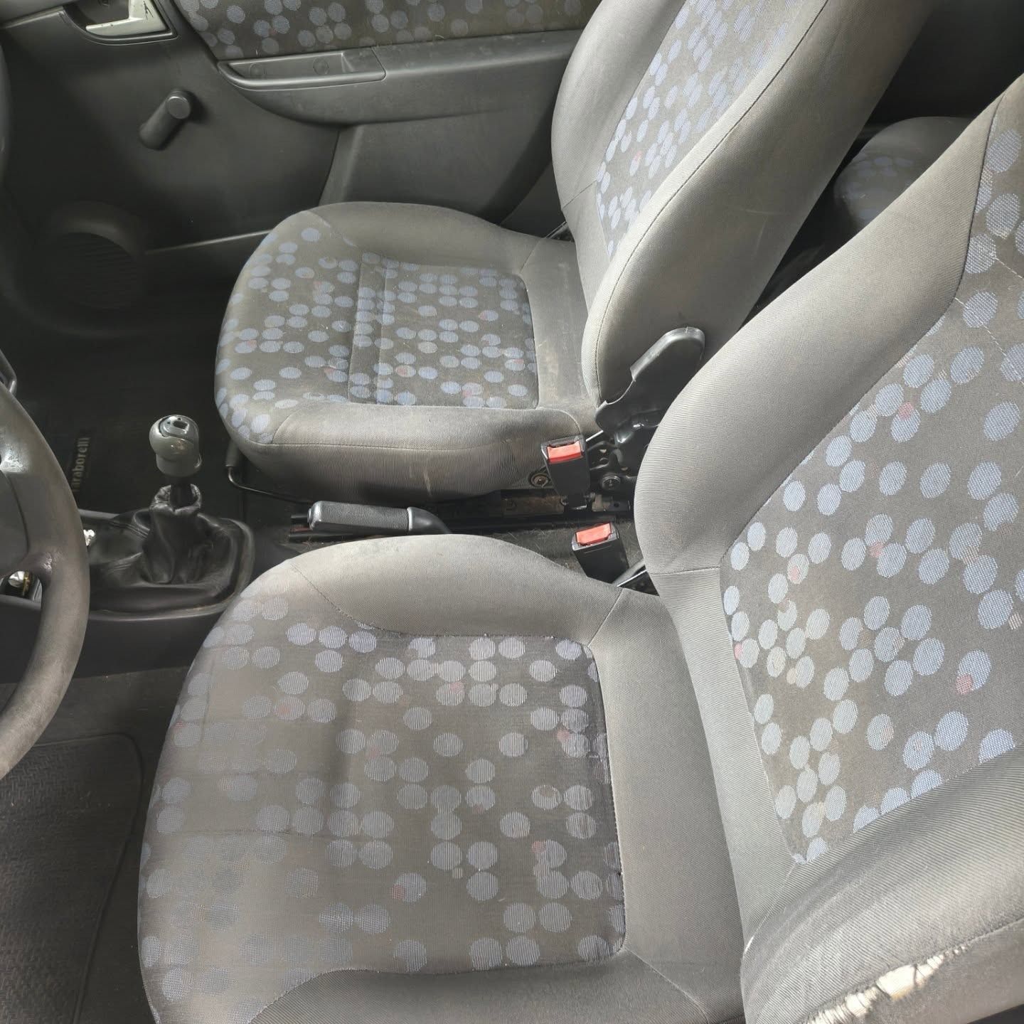 Interior del coche con dos asientos delanteros, tapizado en tela gris