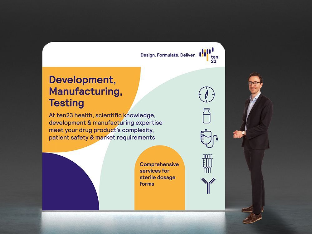 A man in a suit is standing in front of a sign that says development , manufacturing , testing.