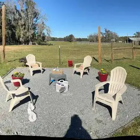 Six beige chairs arranged on gravel patio in sunny outdoor setting.