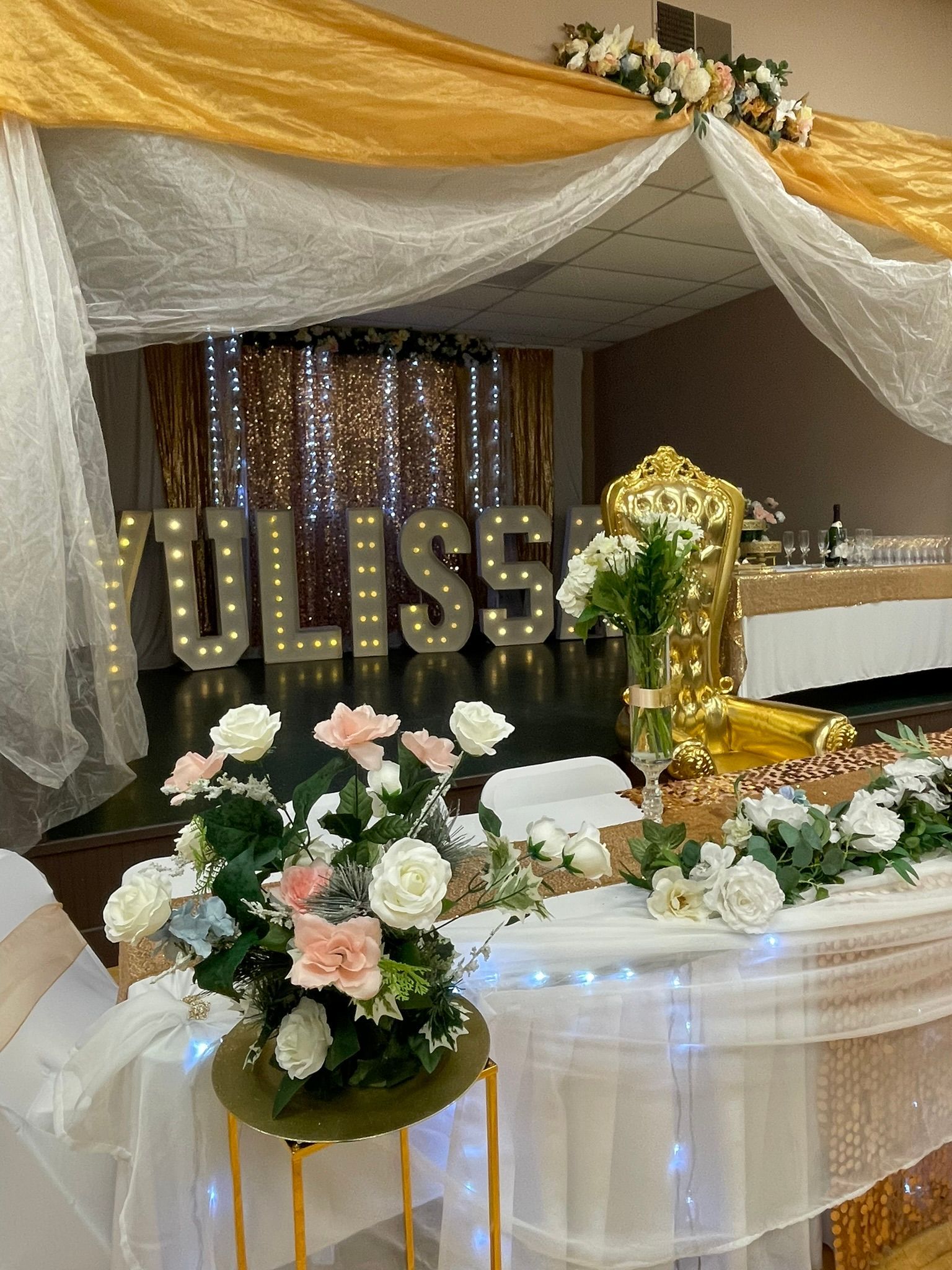 Decorated event space with flowers, lights, and the name 