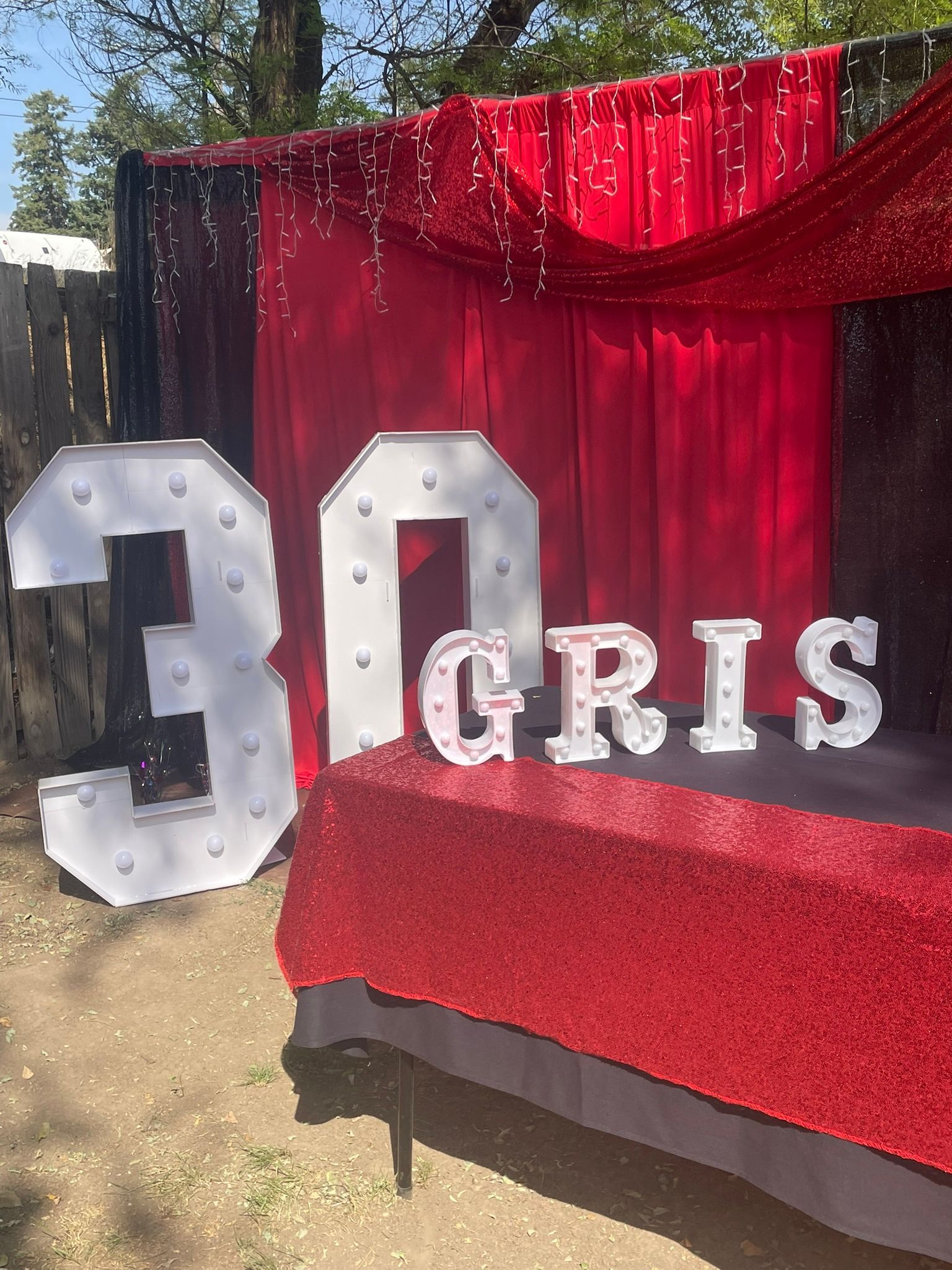Decorated backdrop for a party, featuring red and black fabrics, illuminated 