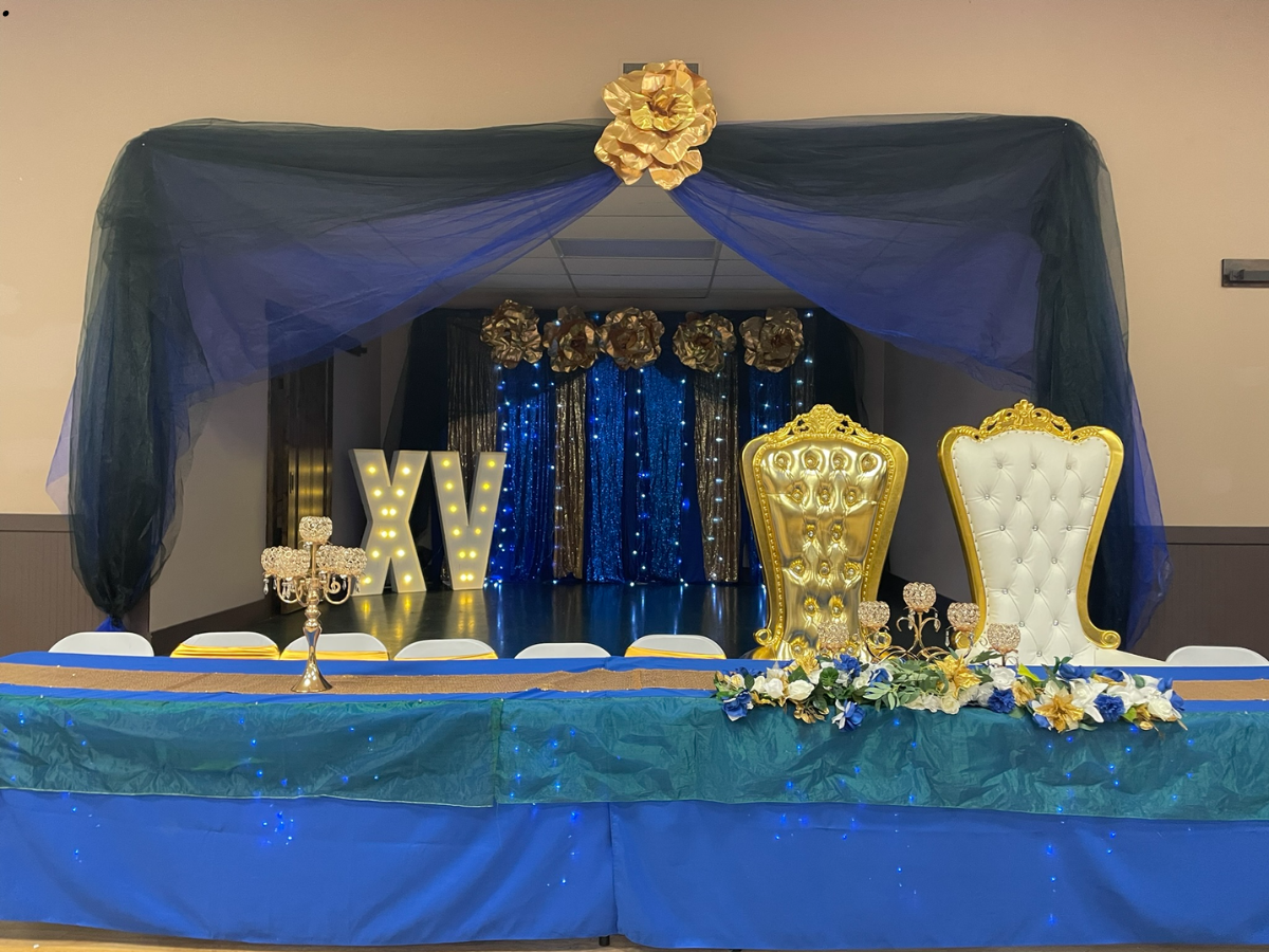 Event stage with blue and gold decorations, including chairs, draping, and