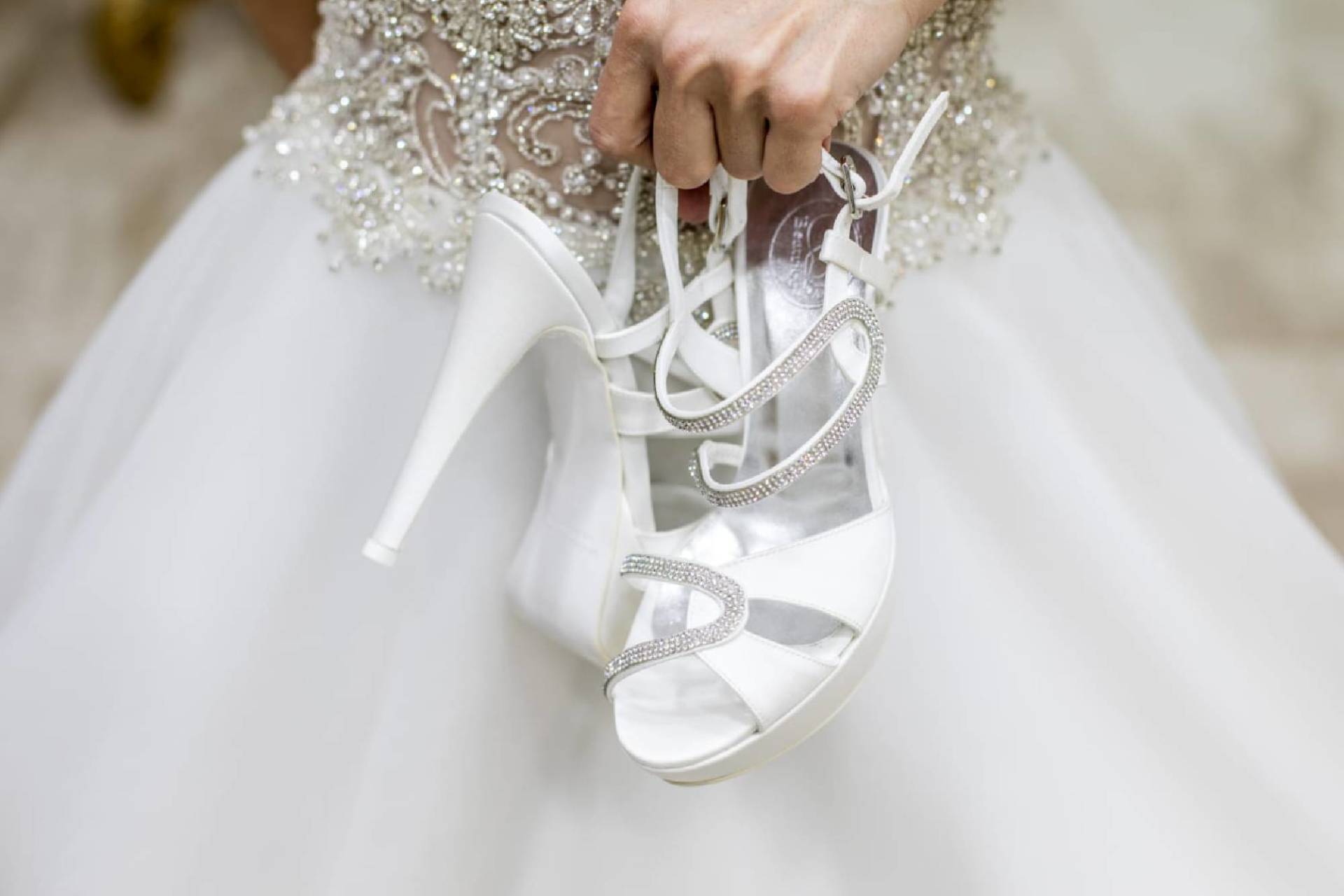 modella che tiene in mano un paio di scarpe da sposa