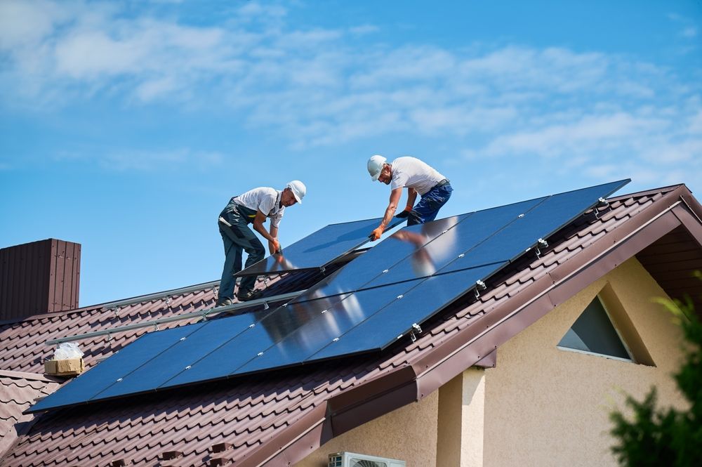 Two men are installing solar panels on the roof of a house.