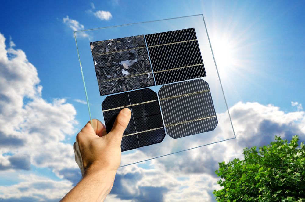 A person is holding a solar panel in front of a blue sky.