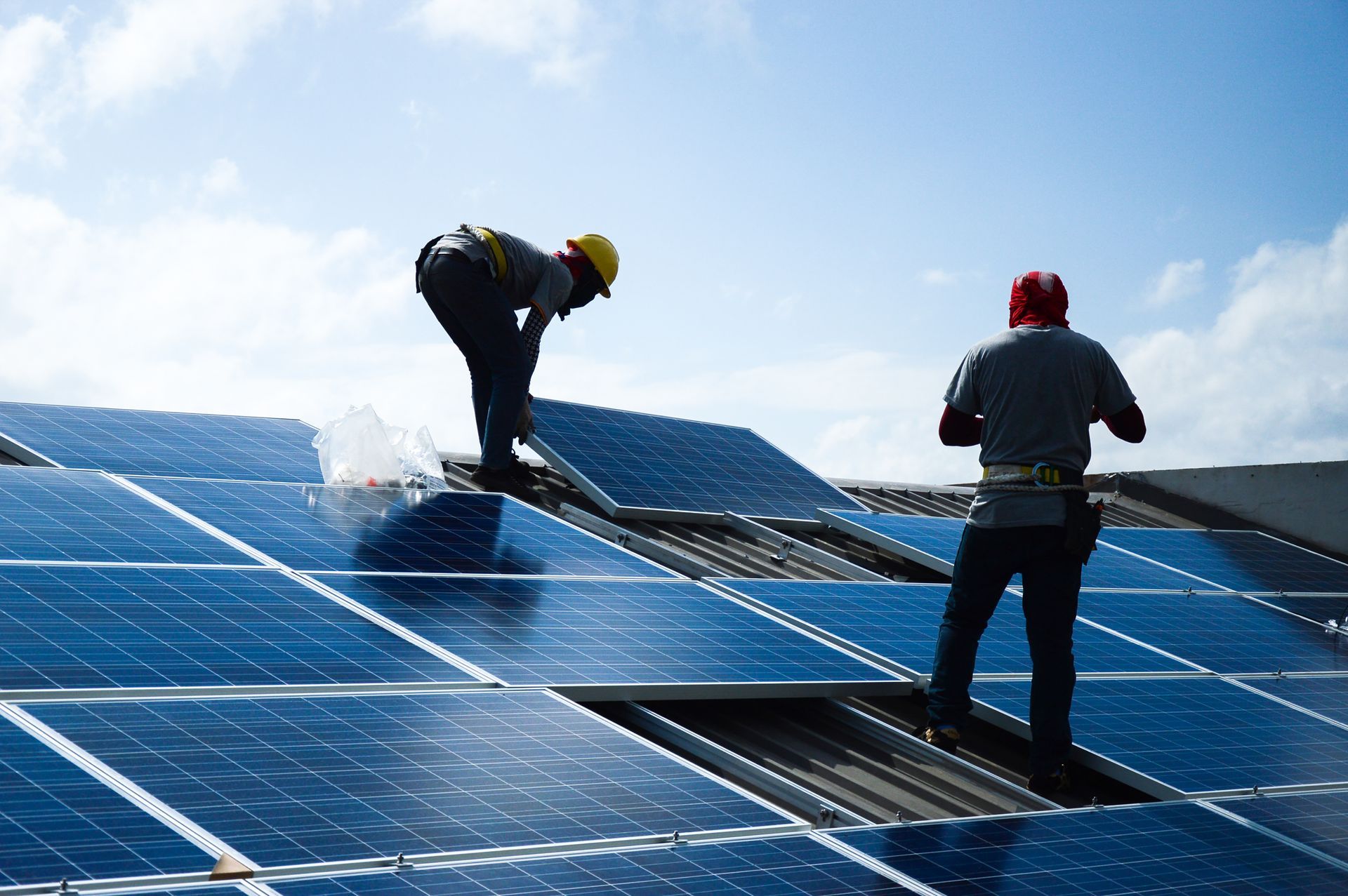 Two men are installing solar panels on the roof of a building.
