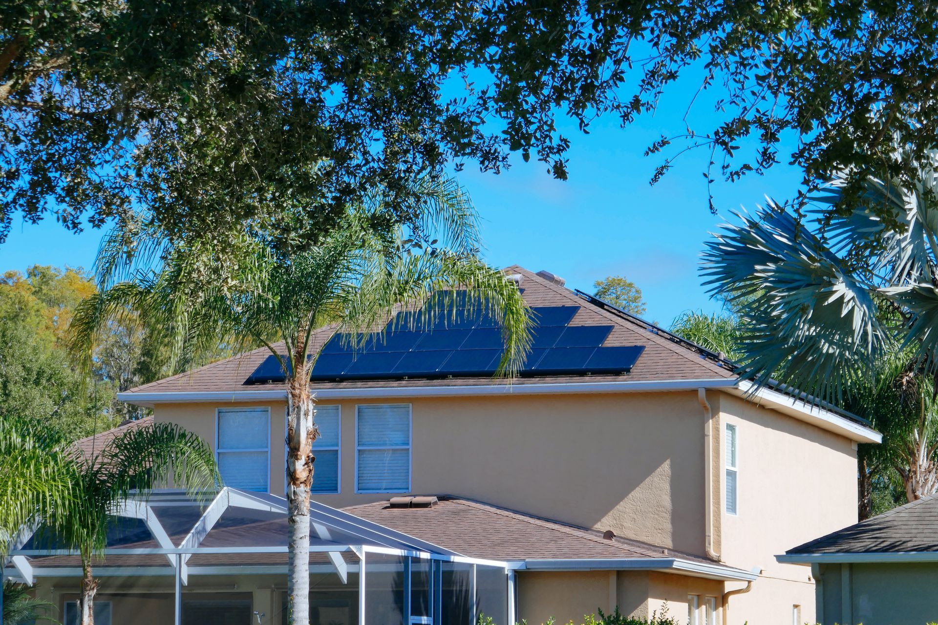 A house with solar panels on the roof is surrounded by trees.