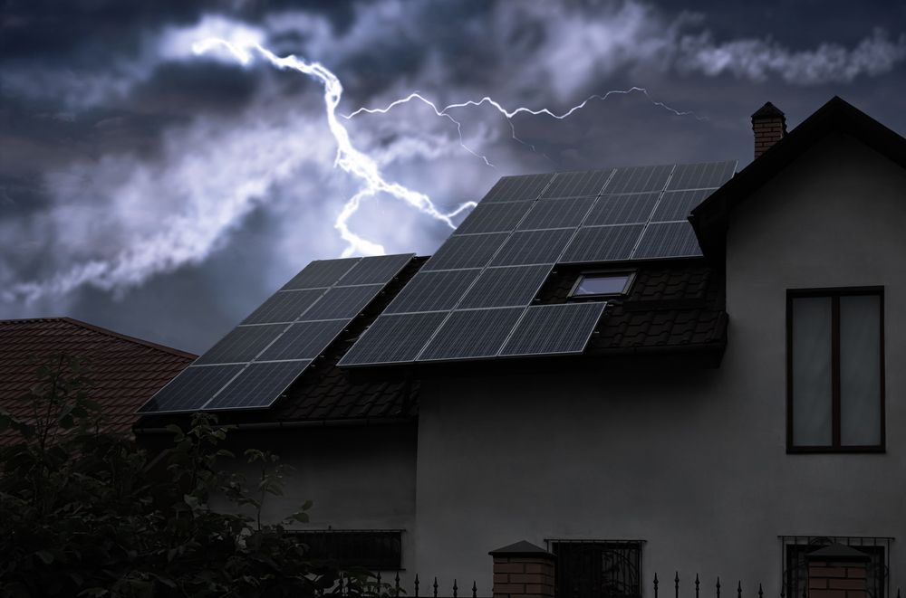 Lightning strikes over a house with solar panels on the roof.