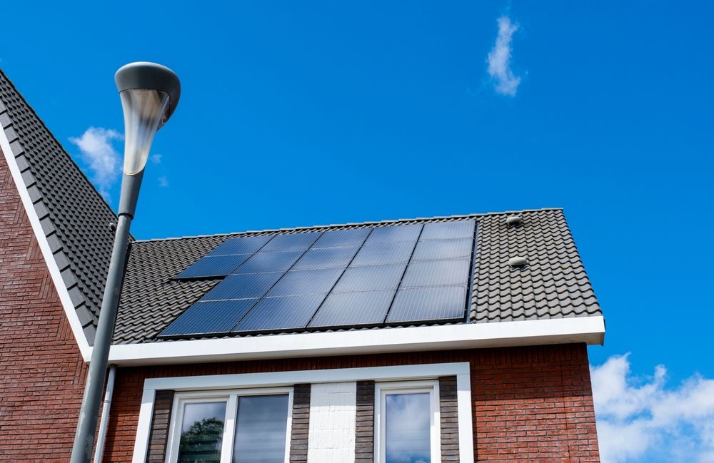 A brick house with solar panels on the roof and a street light.