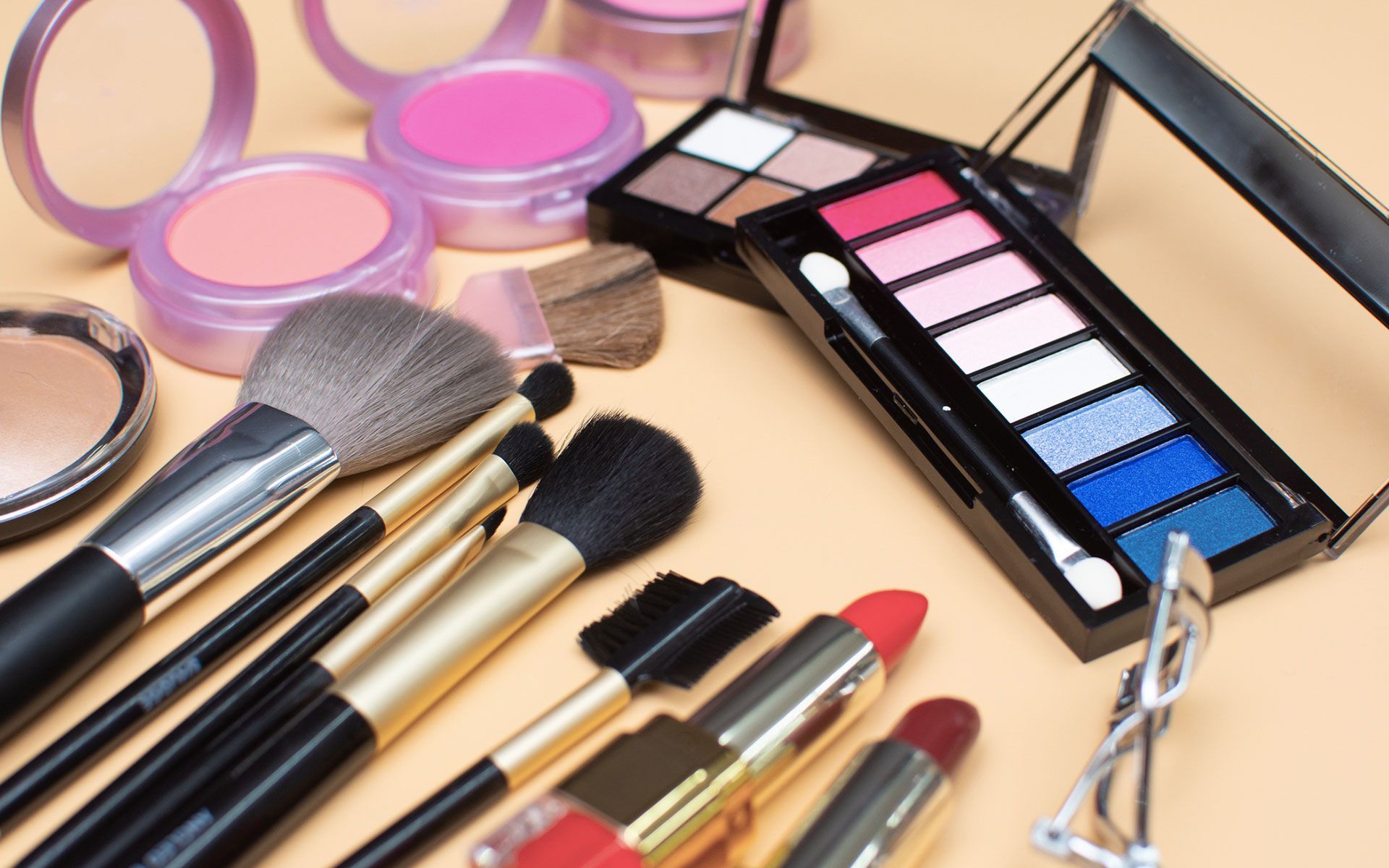 A table topped with a variety of makeup products and brushes.