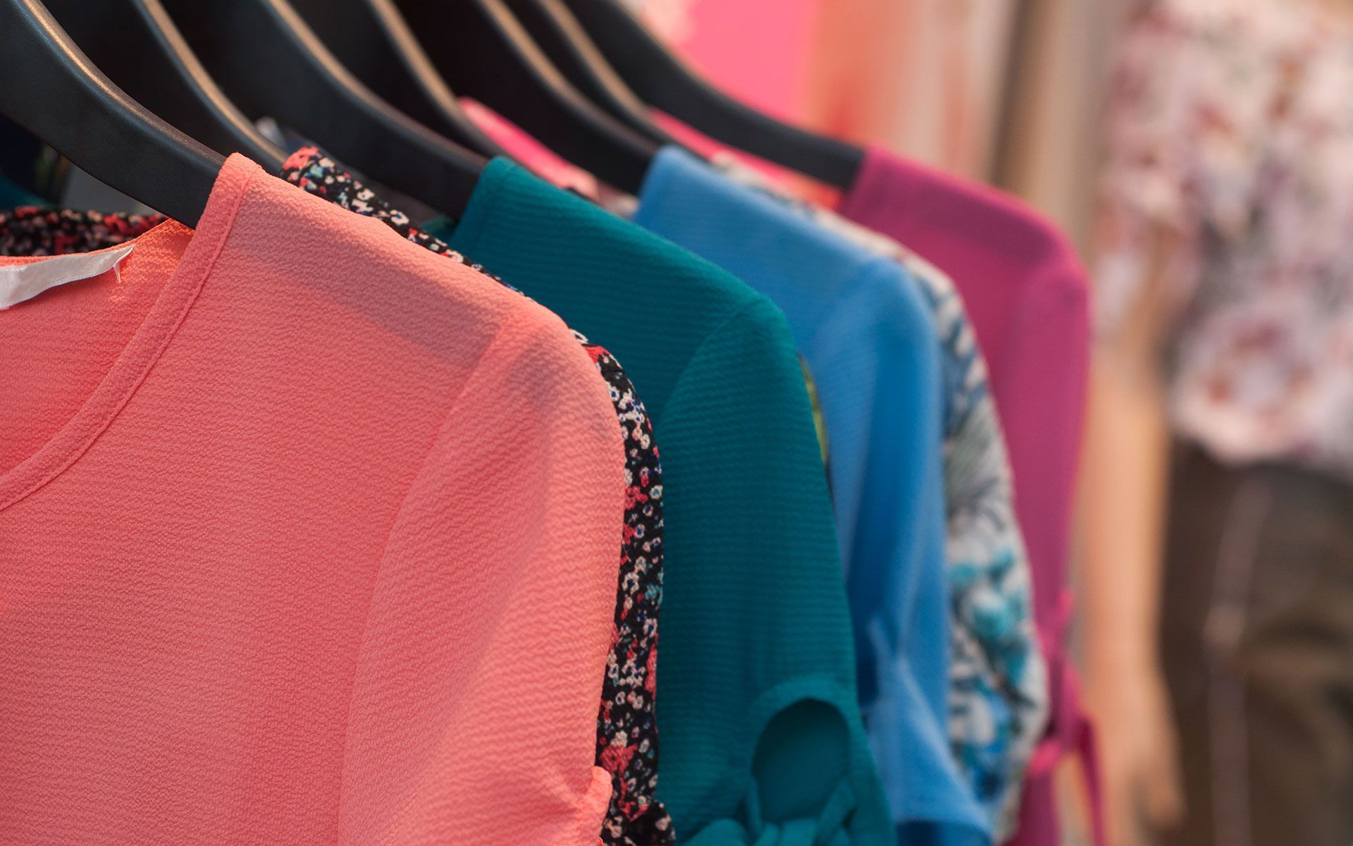 A row of colorful shirts hanging on a rack in a store.