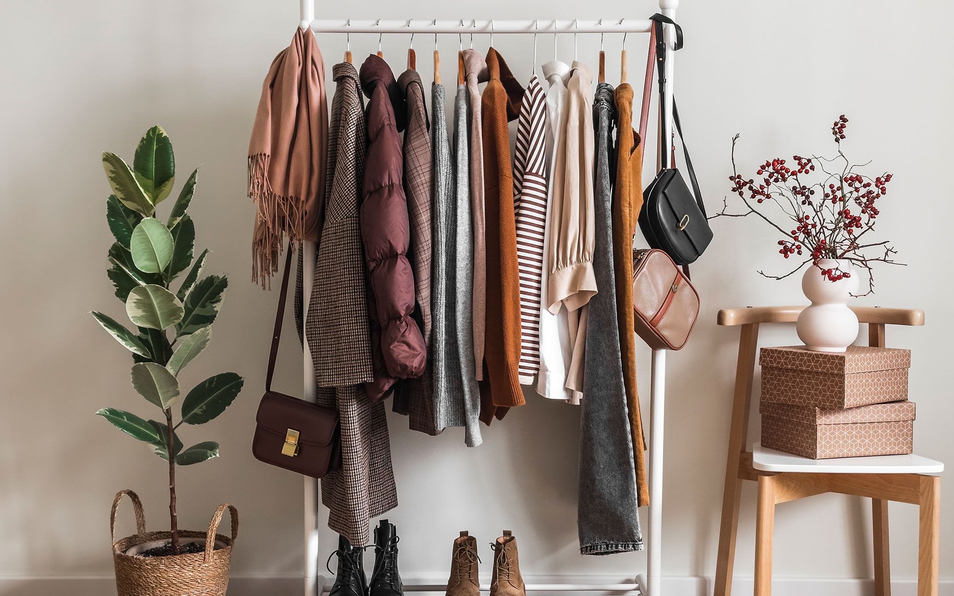 A clothes rack filled with clothes , shoes , handbags , and a plant.