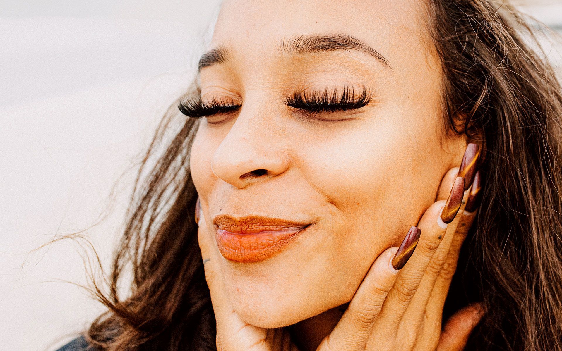 A close up of a woman 's face with her hand on her face.