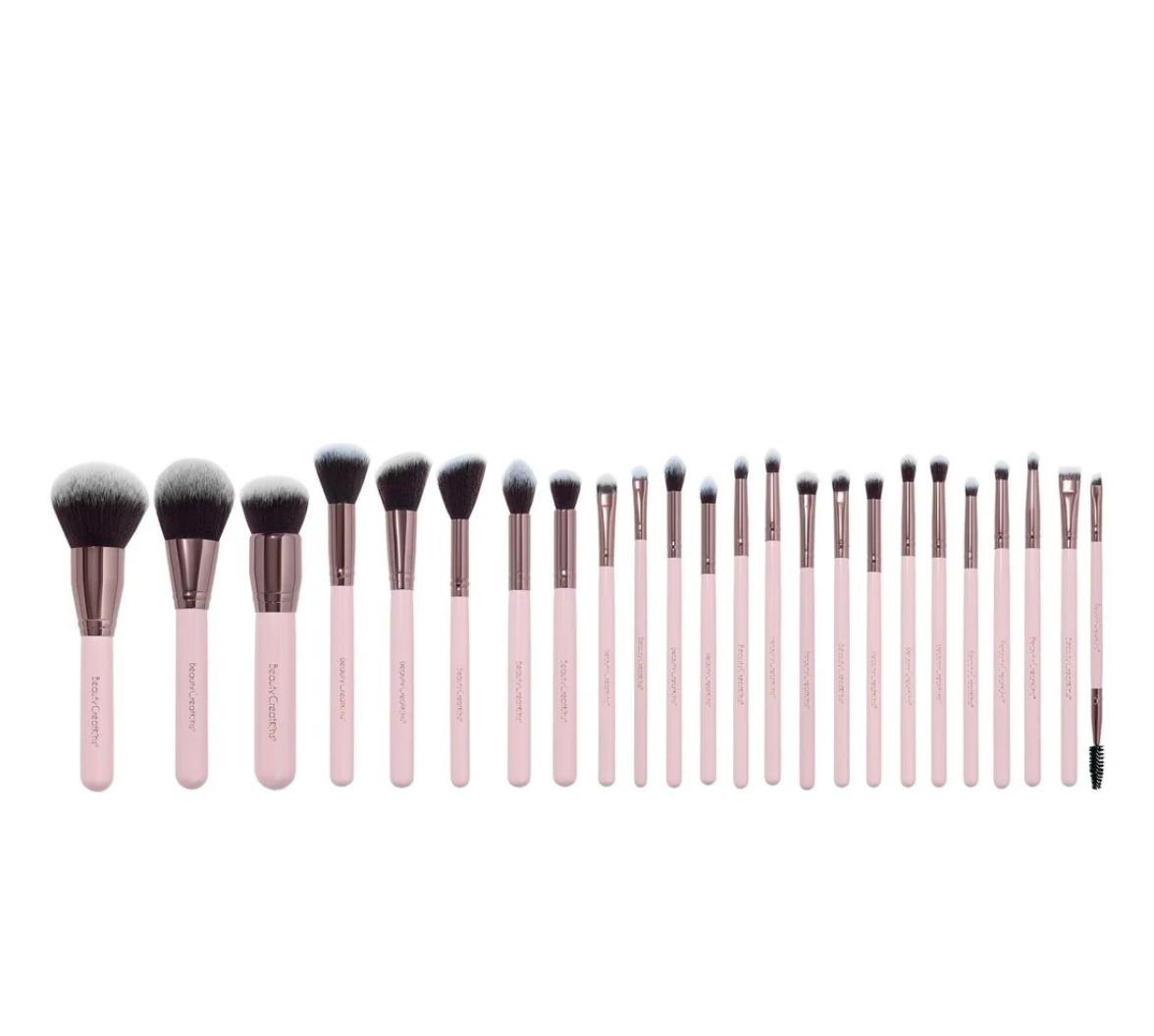 A bunch of makeup brushes are lined up in a row on a white background.