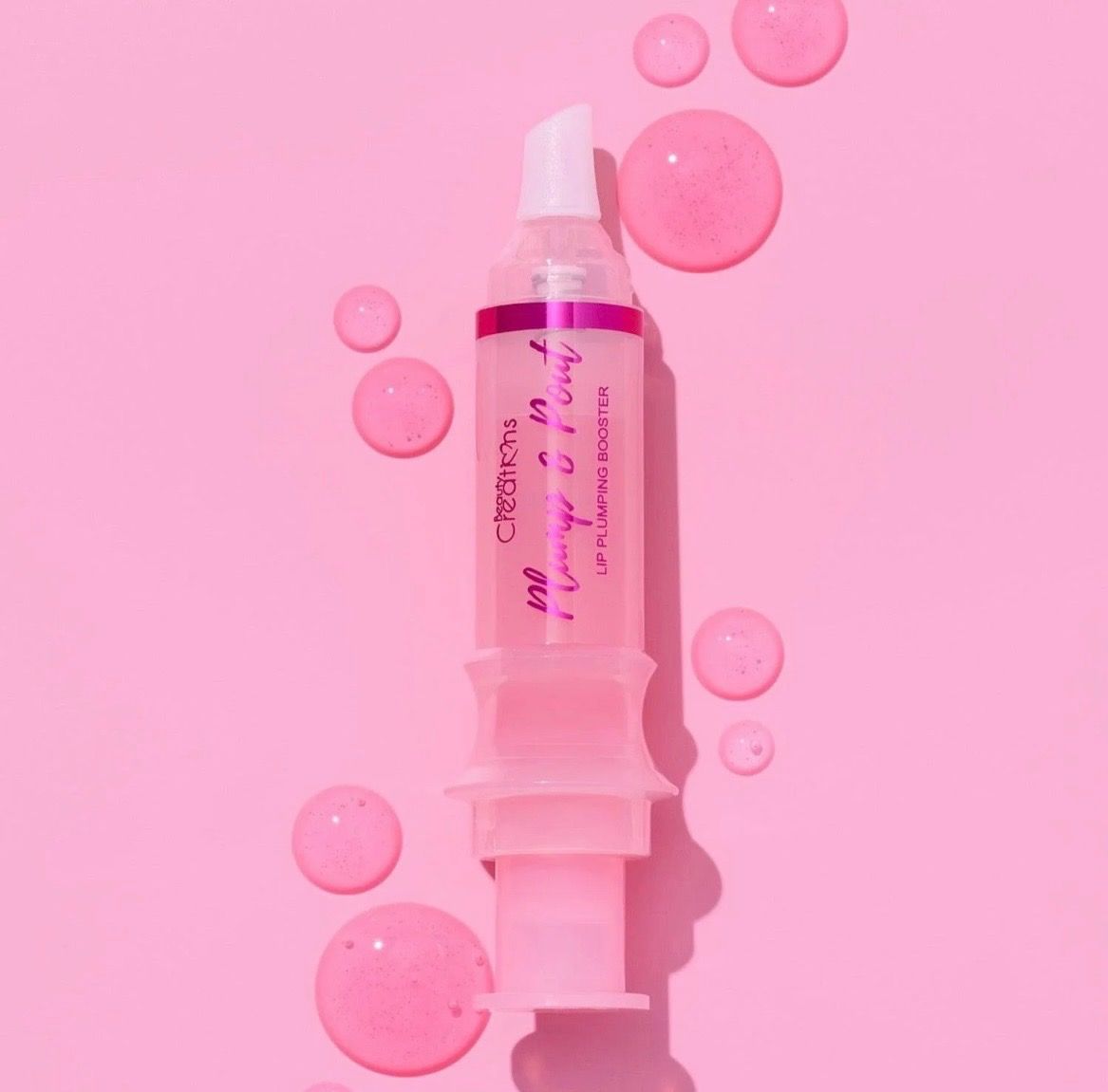 A syringe filled with pink liquid on a pink surface.
