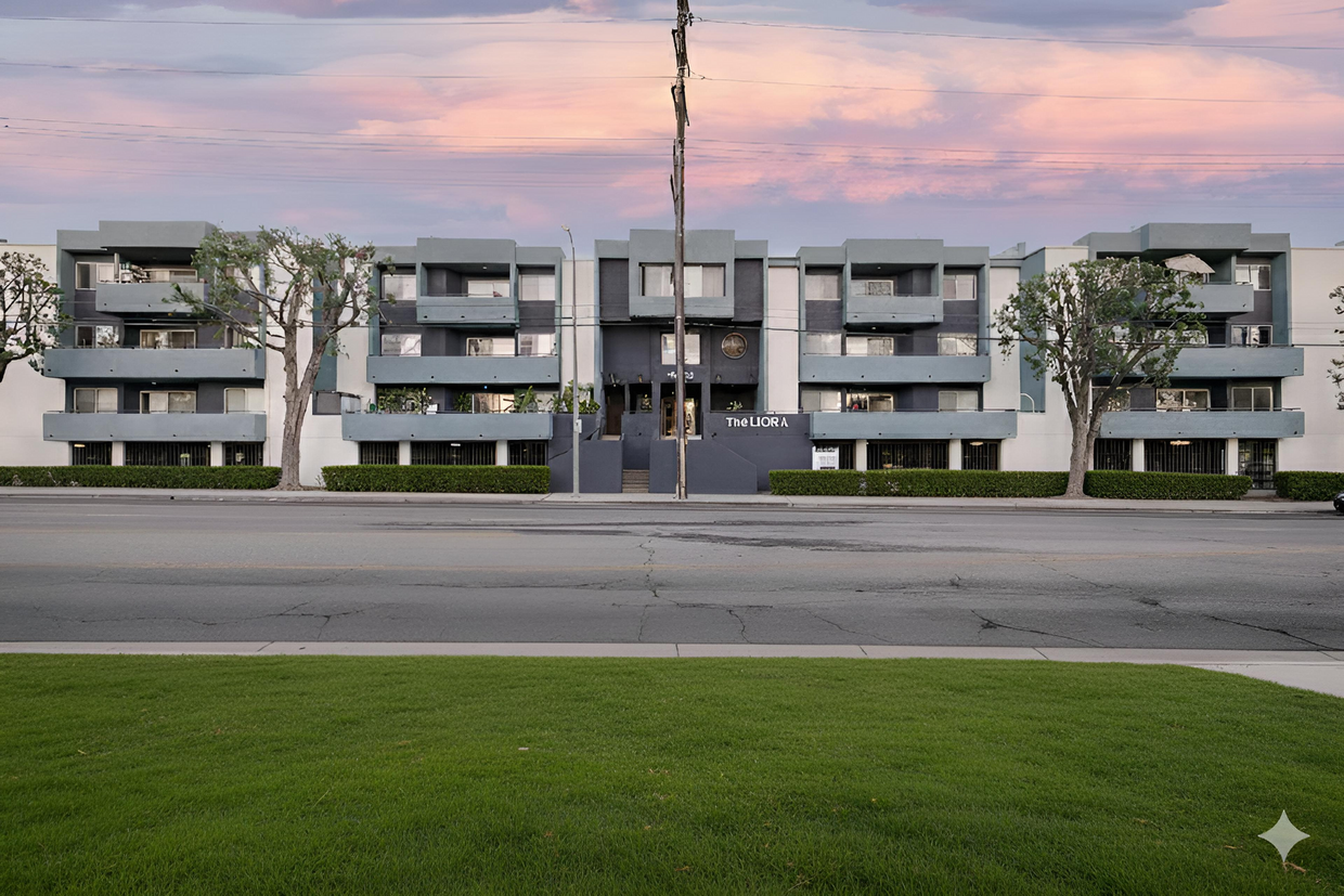 Beige apartment building with stairs leading to the entrance. Palm tree in front.