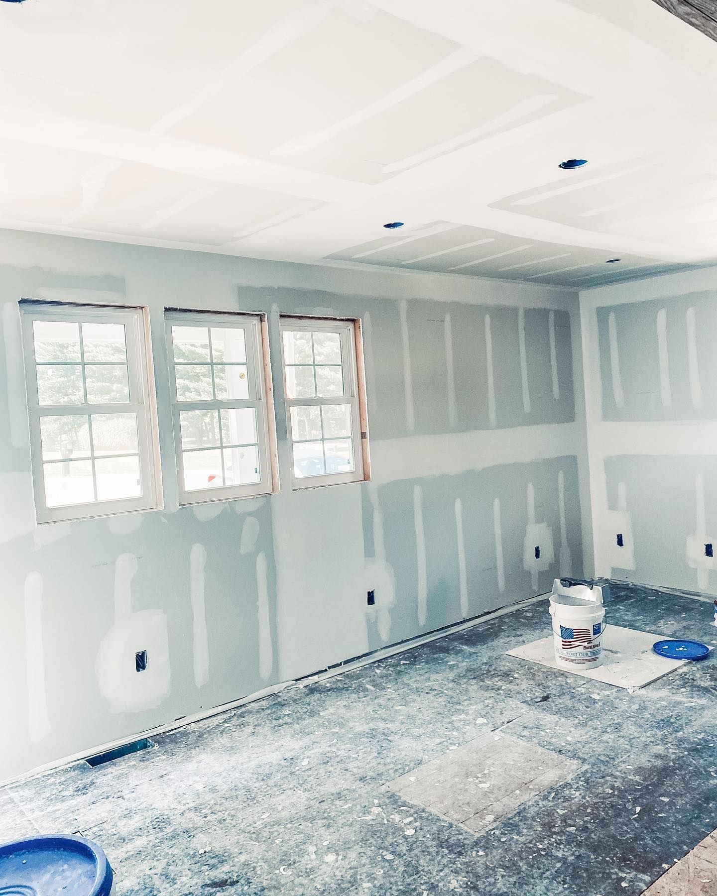 A room that is being painted with a bucket of paint on the floor.