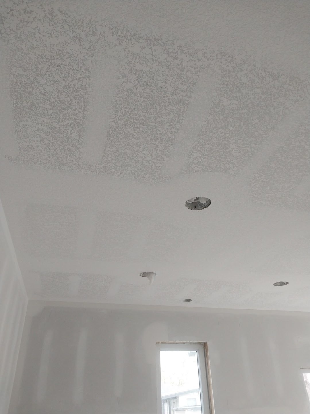 A room with a white ceiling and a window.