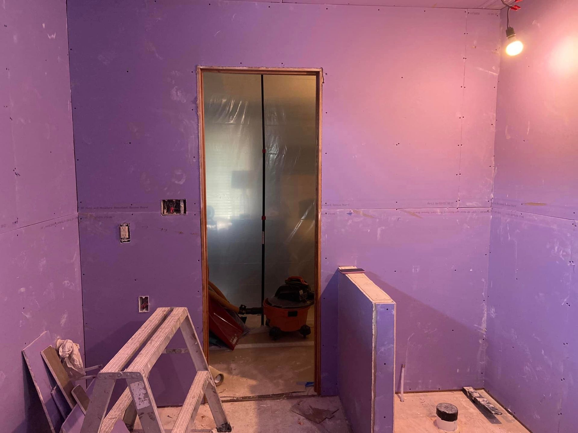 A bathroom under construction with purple walls and a door.