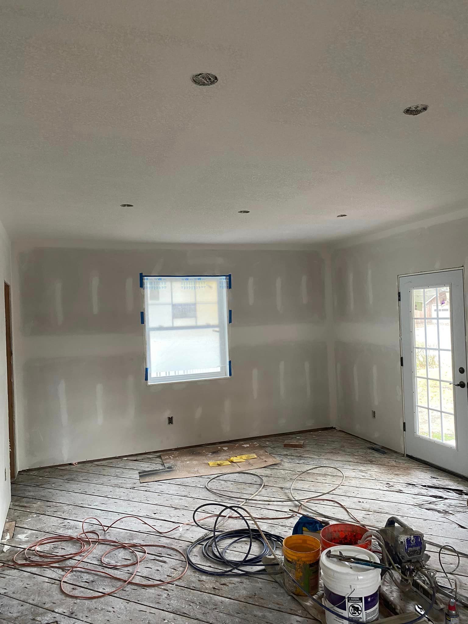 A room with a window and buckets of paint on the floor.