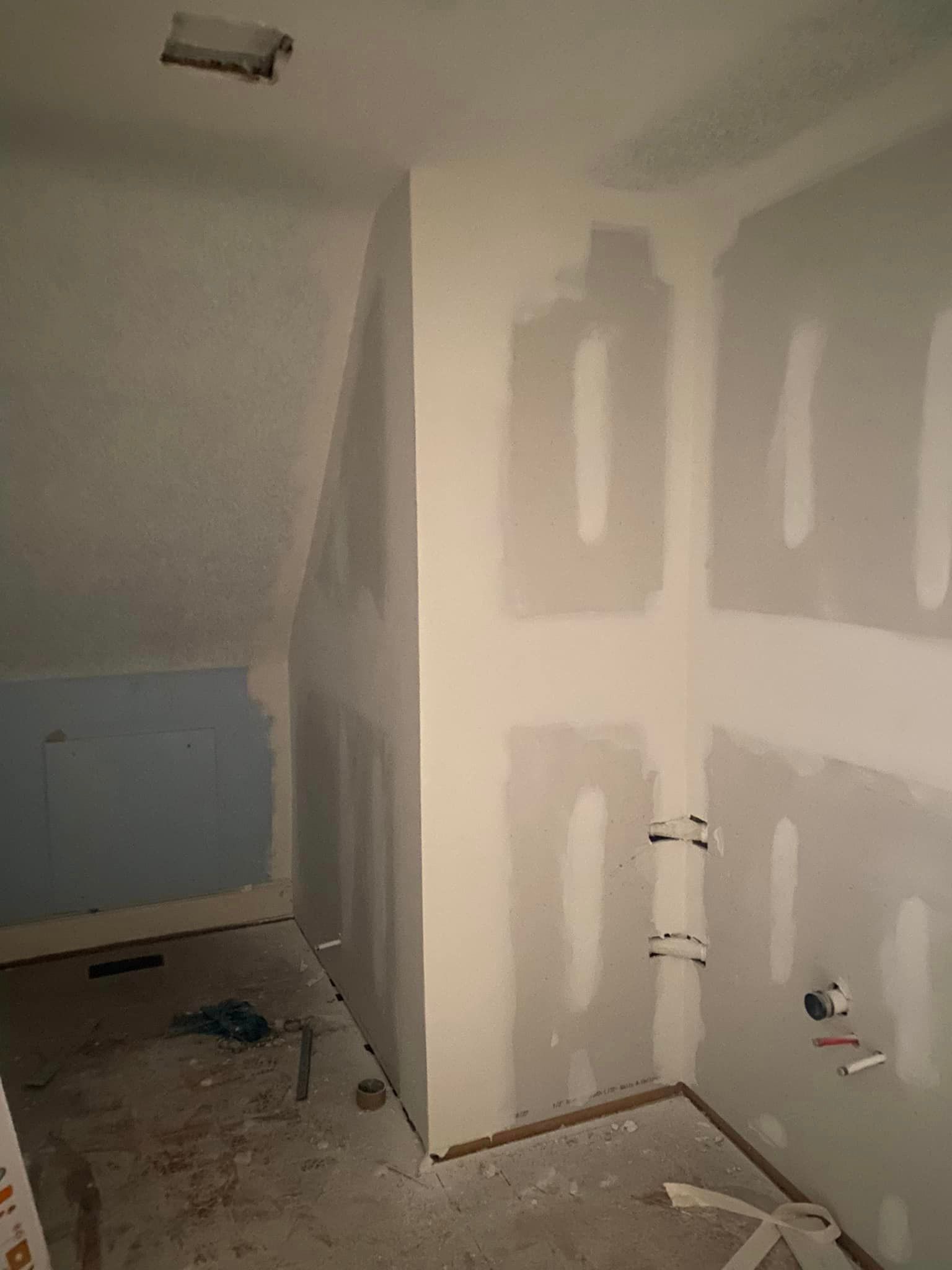 A room with a slanted ceiling and drywall on the walls.