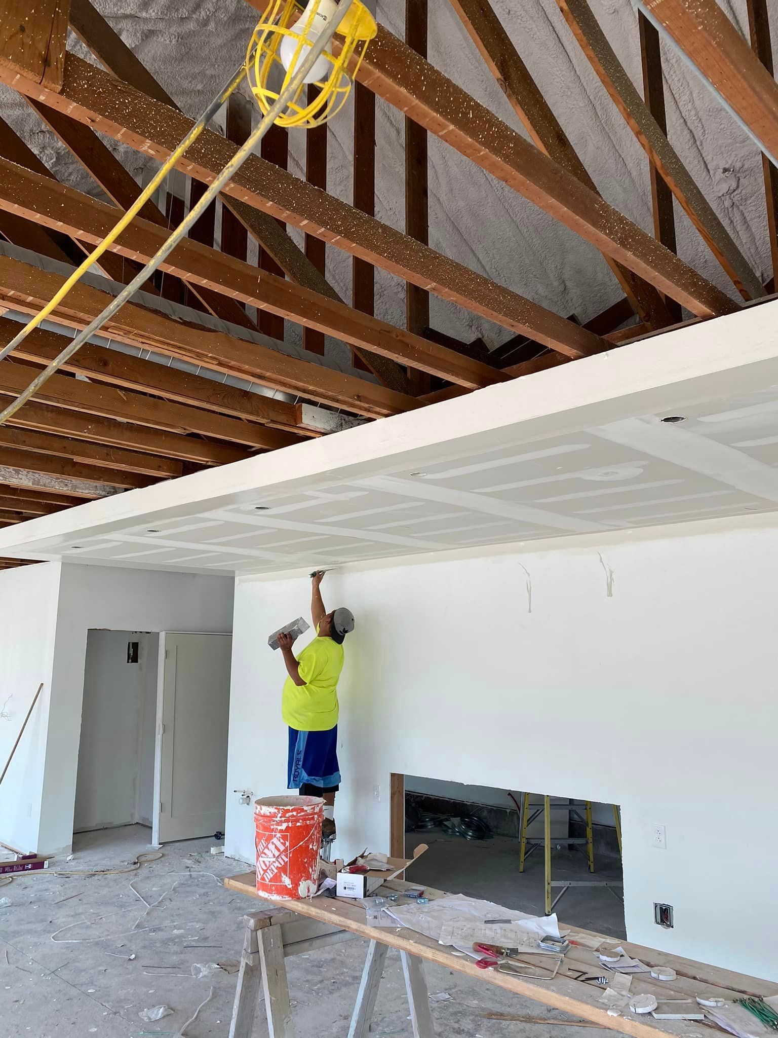 A man is working on a ceiling in a room under construction.