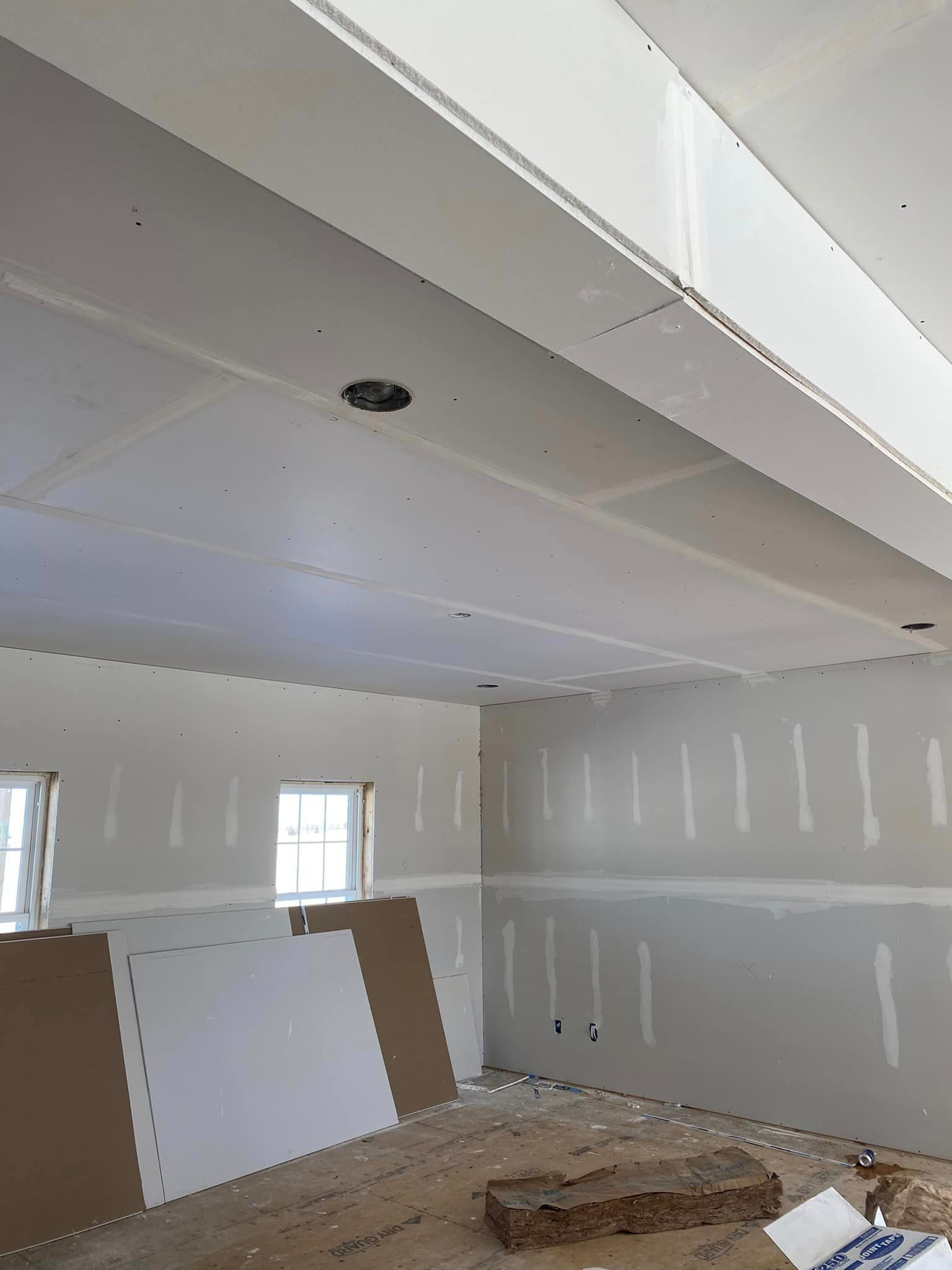 A room that is being remodeled with drywall on the walls and ceiling.