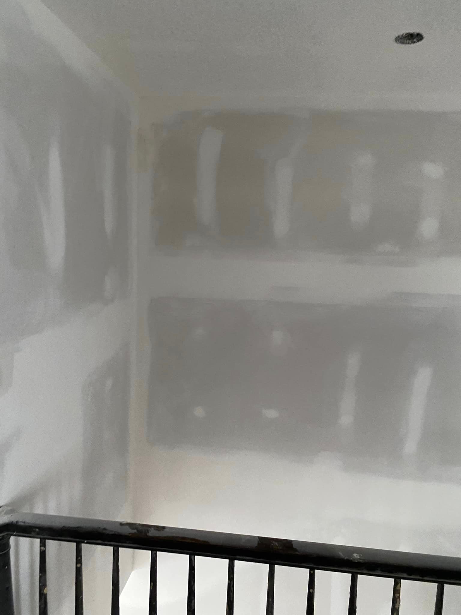 A room with a black railing and white drywall walls.