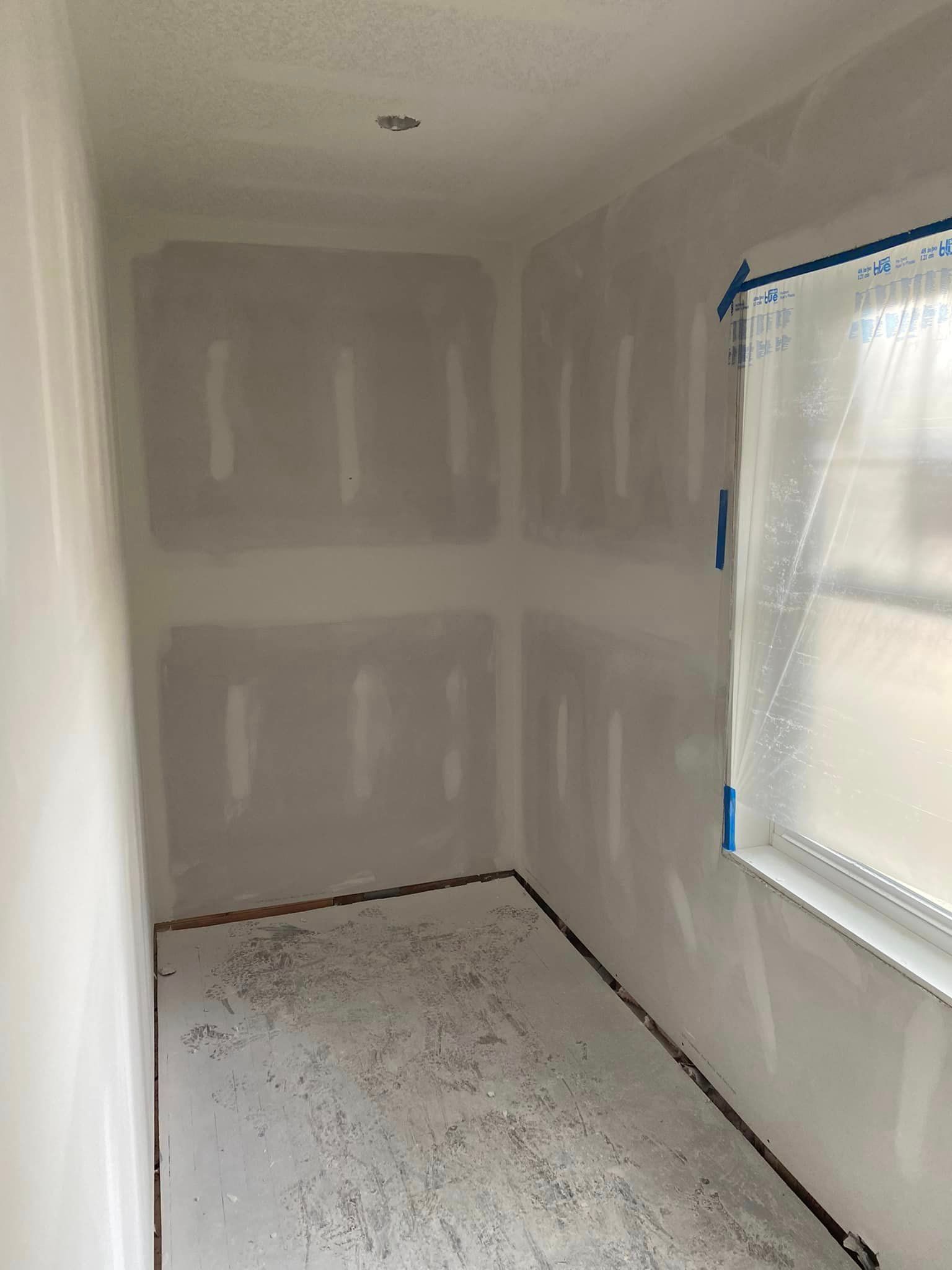 A room with drywall on the walls and a window.